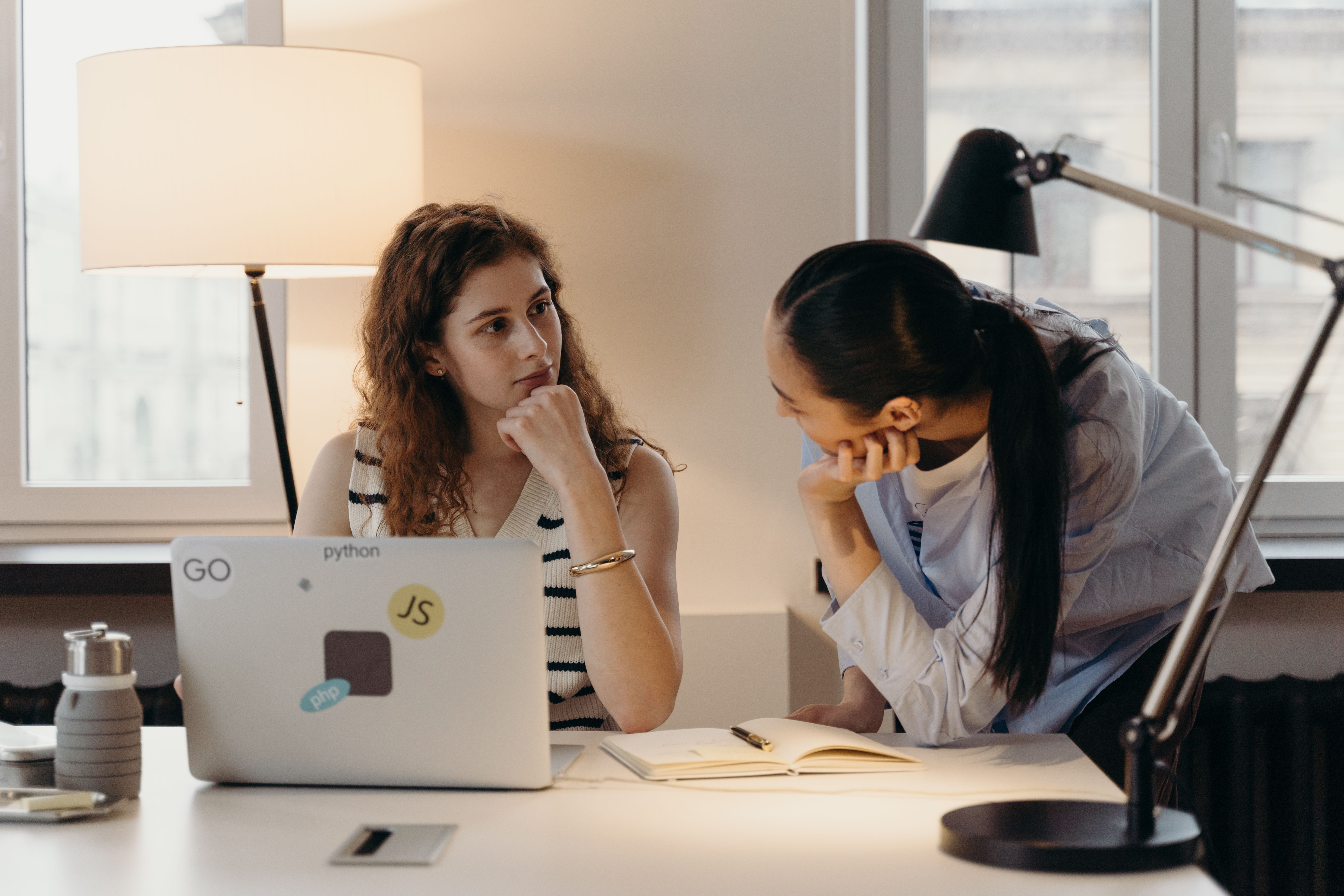 Two women collaborating at a table with a laptop